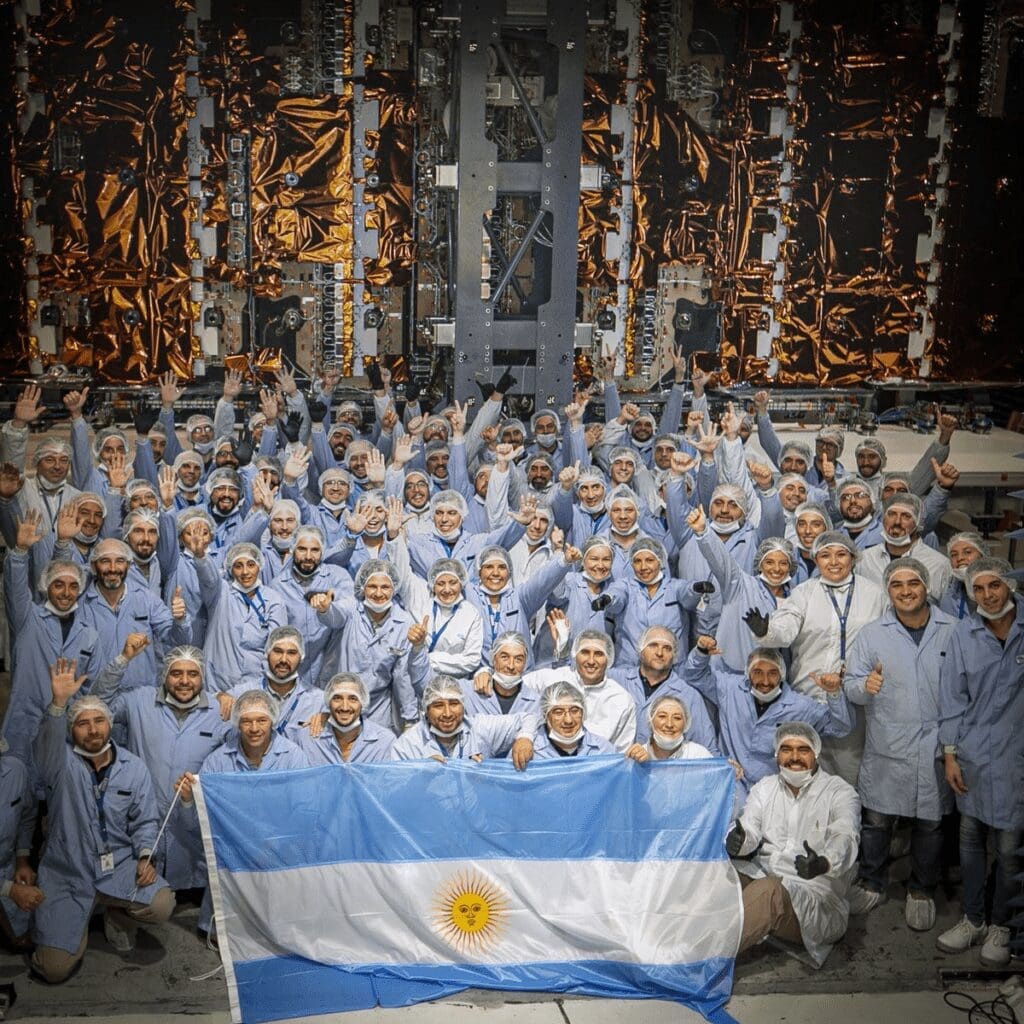 Ingenieros de INVAP posan junto con la bandera argentina frente al satélite de observación de la Tierra SAOCOM.