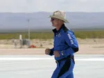Jeff Bezos, founder of Amazon and space tourism company Blue Origin jogs onto the Blue Origin's New Shepard rocket landing pad to pose for photos at the spaceport near Van Horn, Texas, Tuesday, July 20, 2021. (AP Photo/Tony Gutierrez)