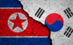 North Korea and South Korea flags background. Cracked wall. Military conflict and war concept
