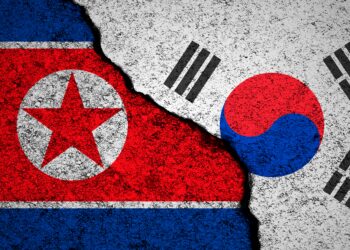North Korea and South Korea flags background. Cracked wall. Military conflict and war concept