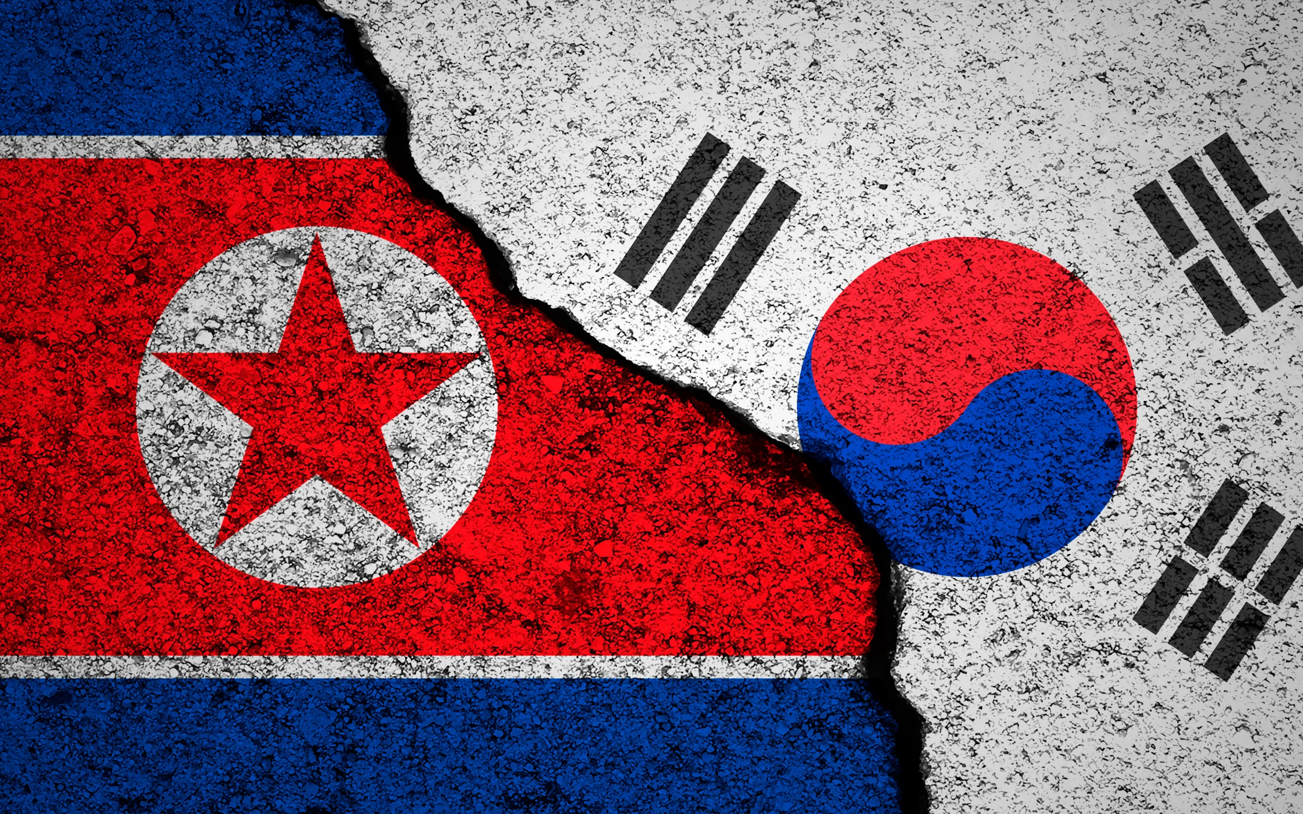 North Korea and South Korea flags background. Cracked wall. Military conflict and war concept