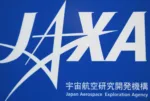 FILE PHOTO: A logo of Japan Aerospace Exploration Agency (JAXA) is seen in front of a gate at the JAXA Chofu Aerospace Center Aerodrome Branch in Tokyo January 22, 2013. REUTERS/Issei Kato