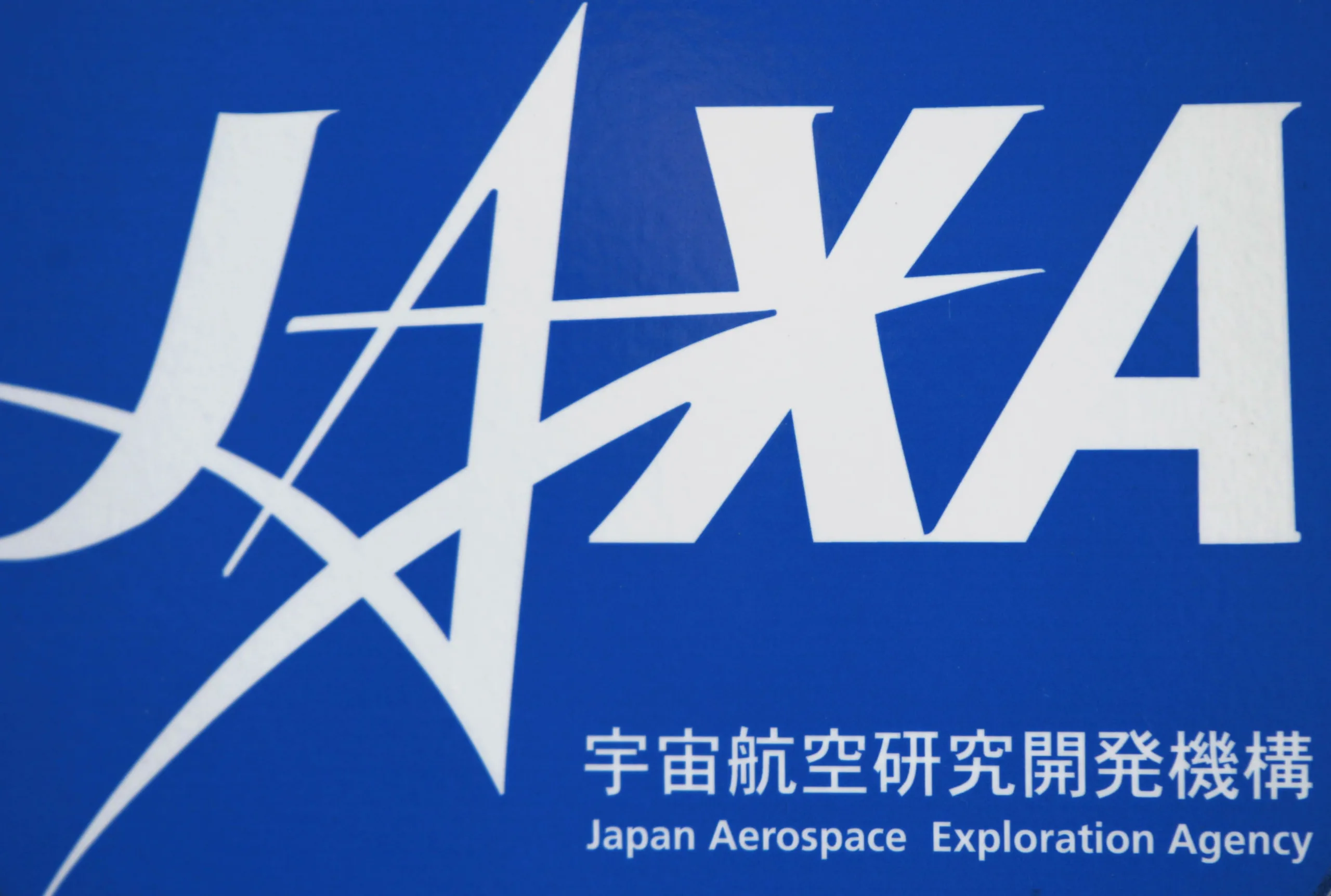 FILE PHOTO: A logo of Japan Aerospace Exploration Agency (JAXA) is seen in front of a gate at the JAXA Chofu Aerospace Center Aerodrome Branch in Tokyo January 22, 2013. REUTERS/Issei Kato