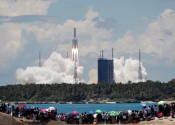 FILE PHOTO: People watch from a beach as the Long March 5 Y-4 rocket, carrying an unmanned Mars probe of the Tianwen-1 mission, takes off from Wenchang Space Launch Center in Wenchang, Hainan province, China July 23, 2020. China Daily via REUTERS