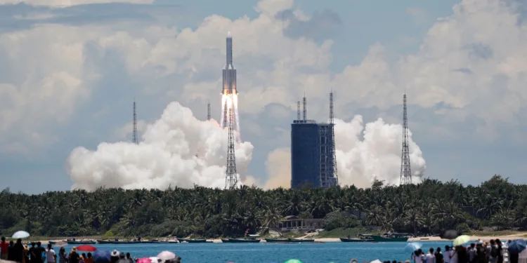 FILE PHOTO: People watch from a beach as the Long March 5 Y-4 rocket, carrying an unmanned Mars probe of the Tianwen-1 mission, takes off from Wenchang Space Launch Center in Wenchang, Hainan province, China July 23, 2020. China Daily via REUTERS