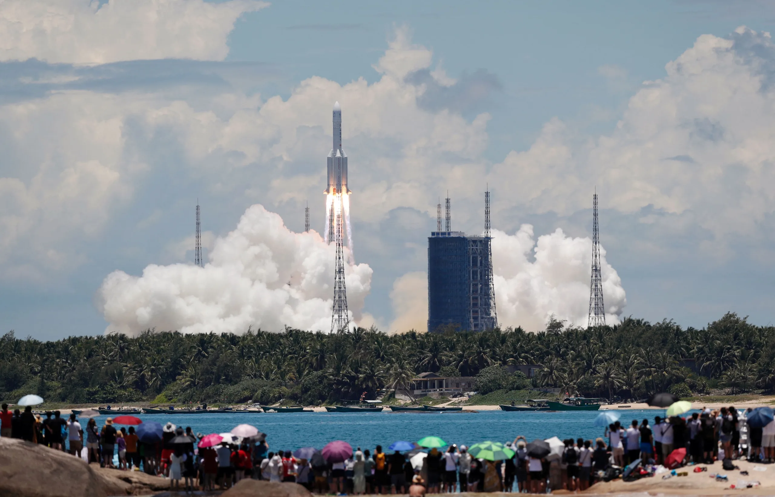 FILE PHOTO: People watch from a beach as the Long March 5 Y-4 rocket, carrying an unmanned Mars probe of the Tianwen-1 mission, takes off from Wenchang Space Launch Center in Wenchang, Hainan province, China July 23, 2020. China Daily via REUTERS