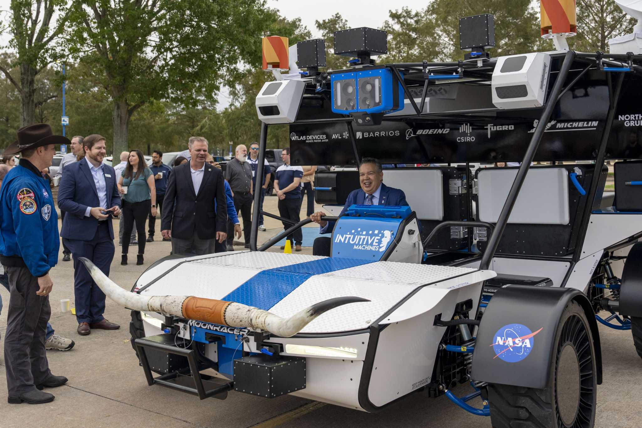 Intuitive Machines Senior Vice President of Space Systems Trent Martin, left center, stands near as Space Center Houston President and CEO William Harris, right, smiles as he sits in the seat of the Intuitive Machines Moonracer Lunar Terrain Vehicle (LTV) during a reveal of the vehicle Thursday, Nov. 7, 2024 in Houston.
