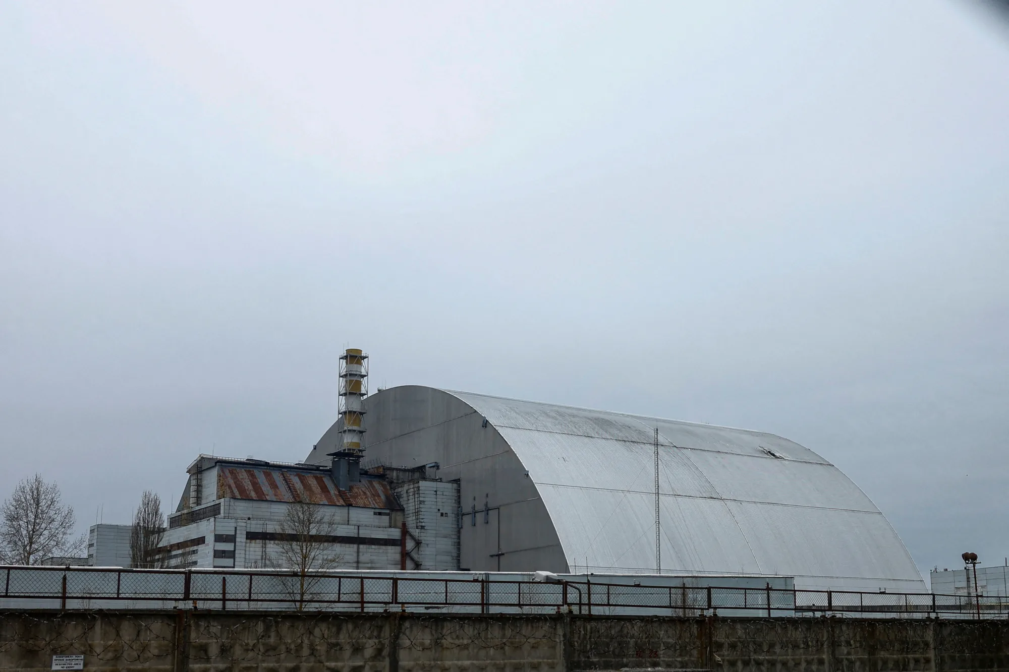 El Nuevo Confinamiento Seguro (NSC) de Chernóbil, que cubre el viejo sarcófago sobre el reactor 4 de la central nuclear. Se observa el agujero de la estructura en la parte superior derecha, causado por el ataque de un gron durante la guerra de Rusia y Ucrania.
