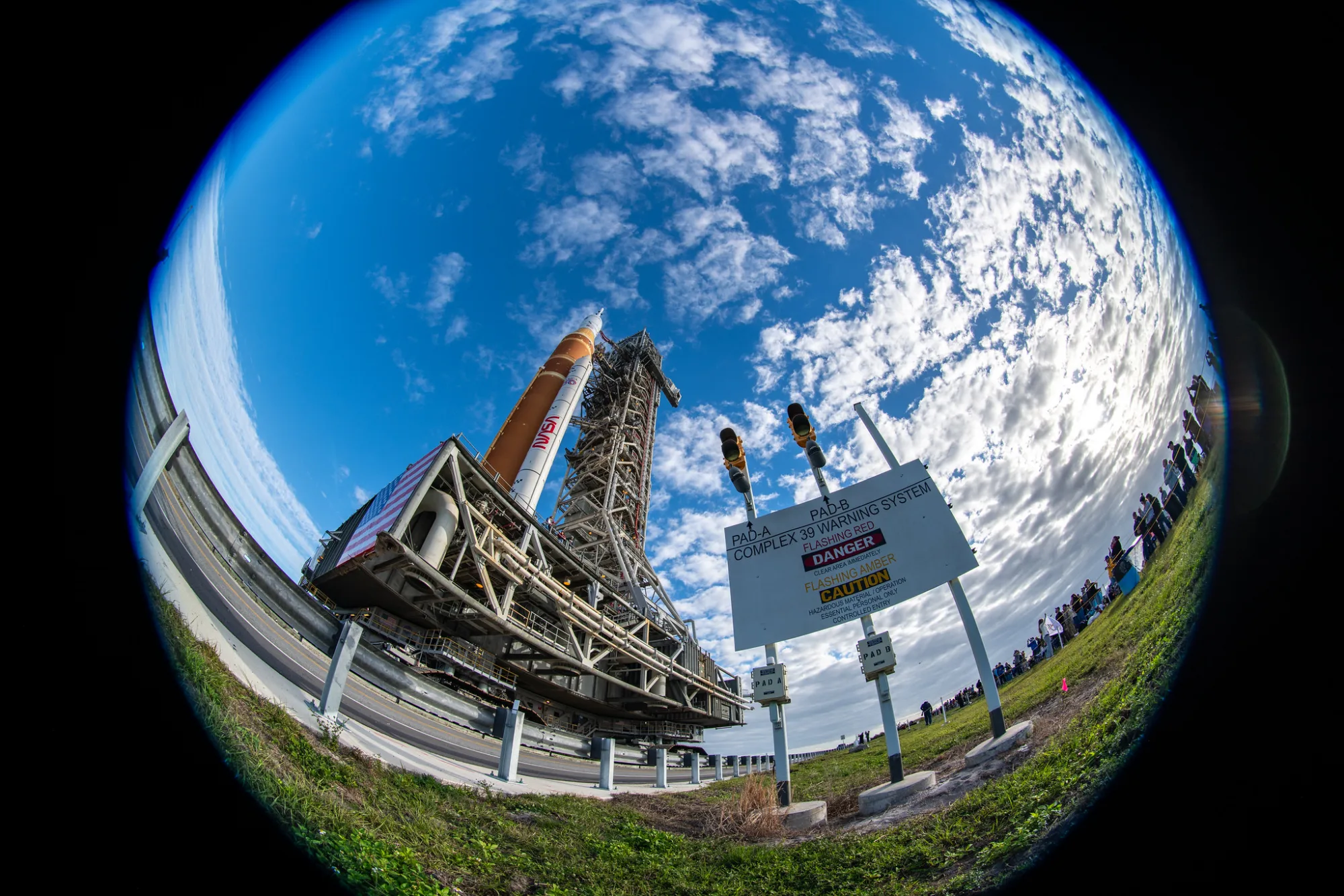 El cohete del Sistema de Lanzamiento Espacial (SLS) de Artemis II de la NASA y la nave espacial Orion, asegurados a la plataforma móvil, son vistos mientras realizan el recorrido de 4.2 millas hacia la Plataforma de Lanzamiento 39B, el sábado 17 de enero de 2026, en el Centro Espacial Kennedy de la NASA en Florida. El vuelo de prueba Artemis II de la NASA llevará al comandante Reid Wiseman, al piloto Victor Glover, y a la especialista de misión Christina Koch, de la NASA, junto al especialista de misión Jeremy Hansen, de la CSA (Agencia Espacial Canadiense), alrededor de la Luna y de regreso a la Tierra a más tardar en abril de 2026. Crédito de la foto: (NASA/Keegan Barber)