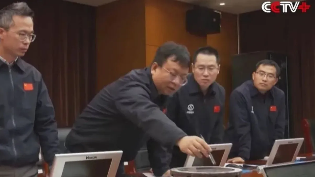 Expertos del equipo de tierra analizando las grietas en la ventana rota de la nave Shenzhou-20.