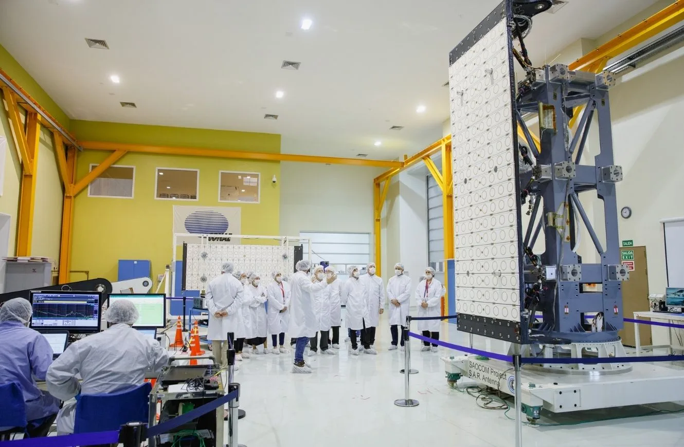 Dentro de las instalaciones del CETT, un grupo de visita observa un prototipo del satélite argentino radar SAOCOM.