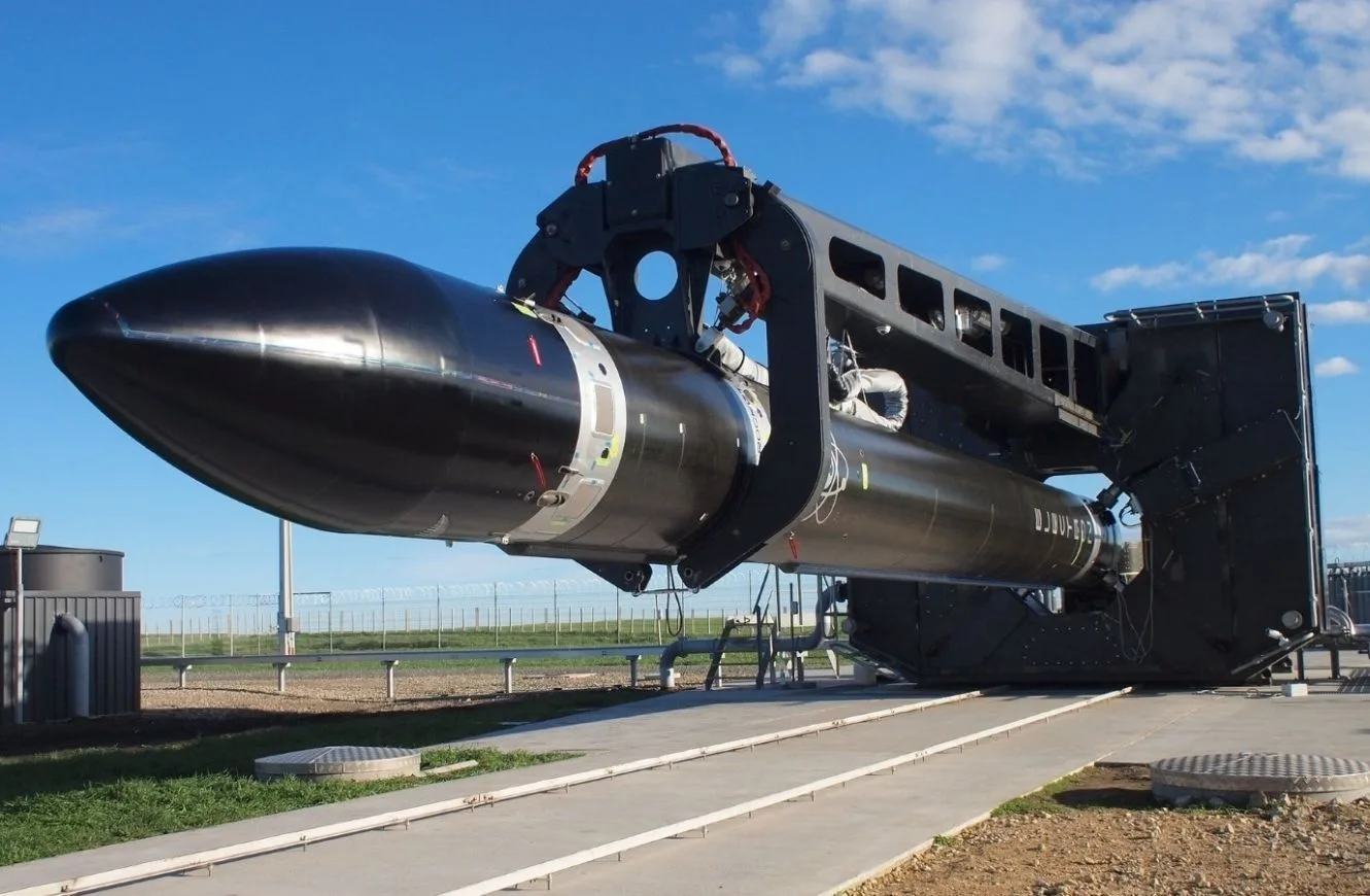 Un cohete Electron en posición horizontal, montado en un banco de integración/ensayo antes de su traslado a la rampa. Es el caballo de batalla de carga pequeña de Rocket Lab que consolidó su operación de lanzamientos frecuentes.