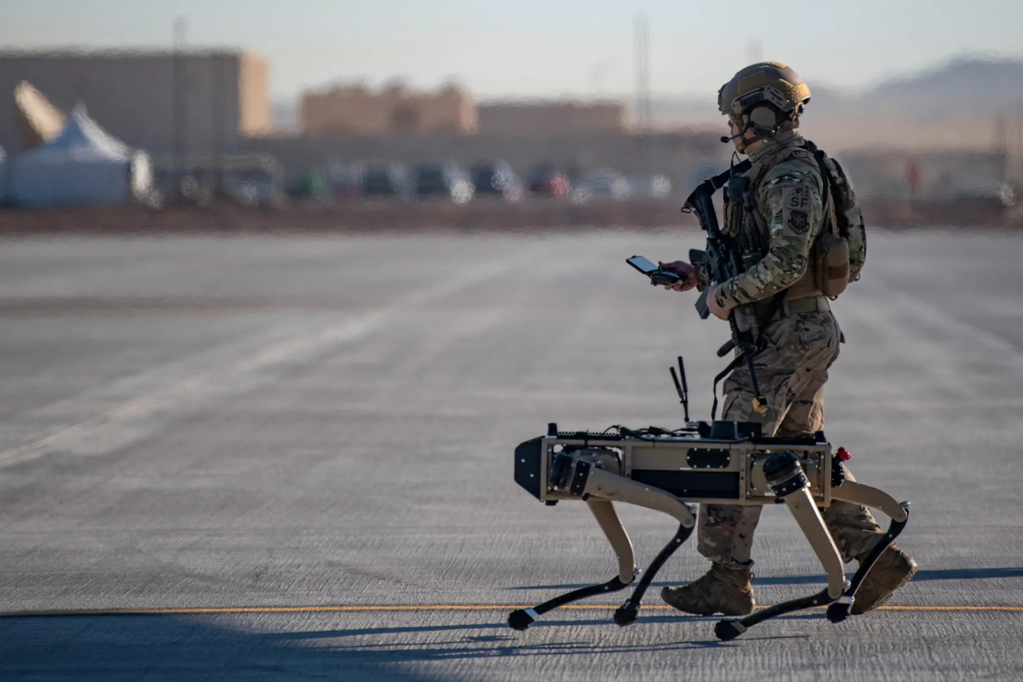 El Sargento Técnico John Rodriguez, del equipo de seguridad del 321º Escuadrón de Respuesta de Contingencia, patrulla con un prototipo Vision 60 de Ghost Robotics en una base simulada austera durante el ejercicio del Sistema Avanzado de Gestión de Batalla en la Base Aérea Nellis, Nevada, el 3 de septiembre de 2020. (Foto de la Fuerza Aérea de los EE. UU. por el Sargento Técnico Cory D. Payne)