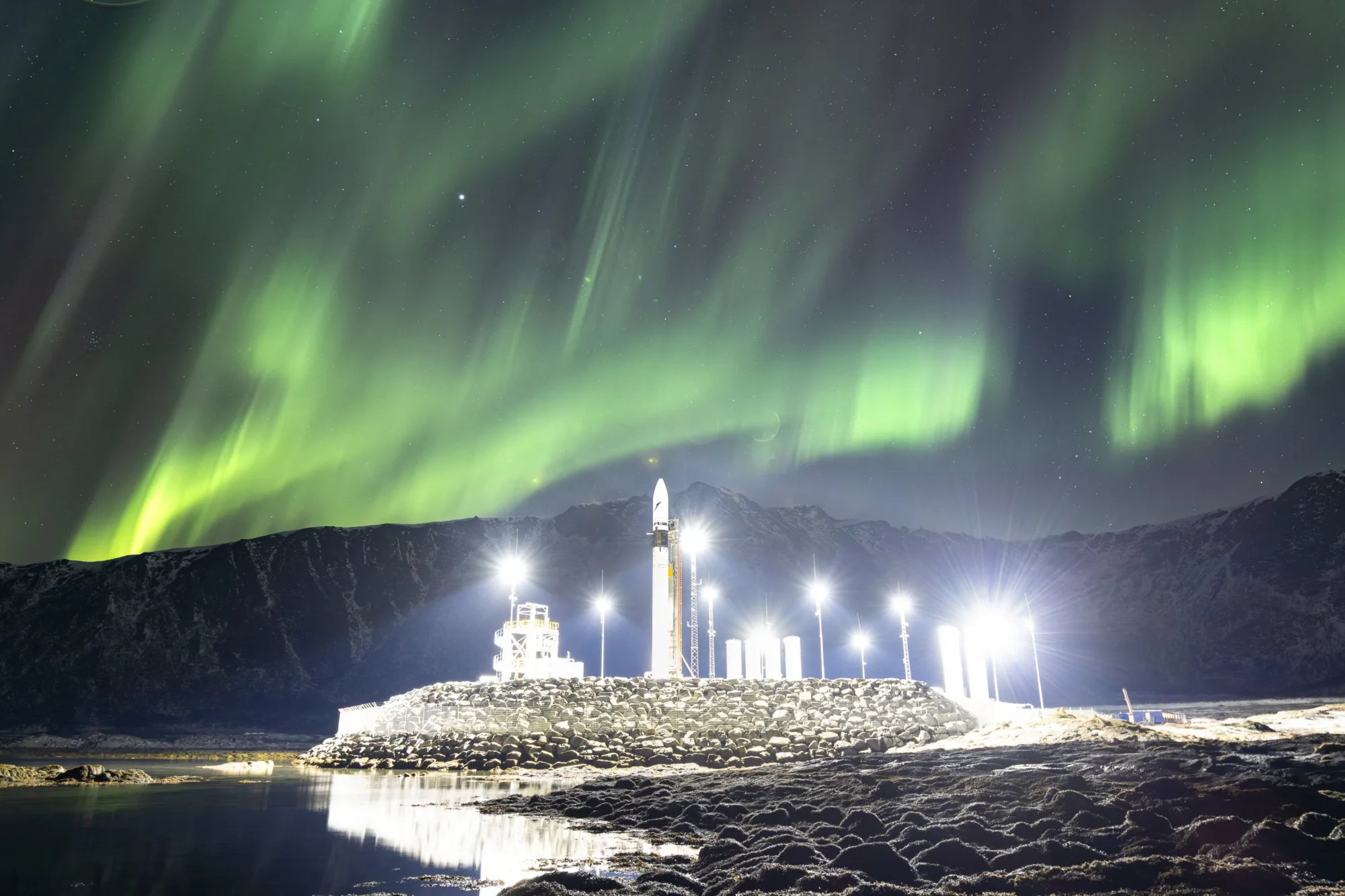 Impresionante imagen del cohete Spectrum de Isar Aerospace en el Puerto Espacial Andøya, en el norte de Noruega, con auroras boreales iluminando el cielo nocturno.