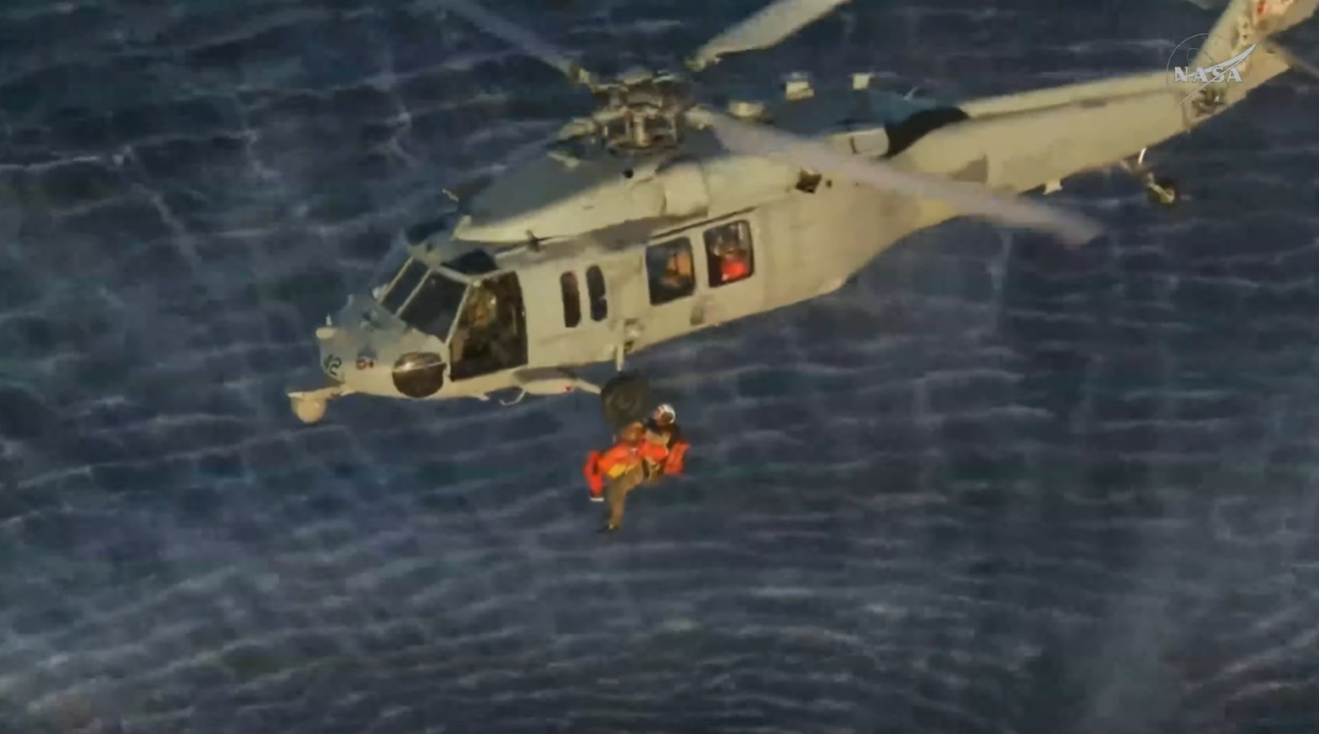 El comandante de la misión Artemisa II y astronauta de la NASA, Reid Wiseman, está siendo izado a bordo de un helicóptero militar estadounidense antes de ser transportado al USS John P. Murtha.