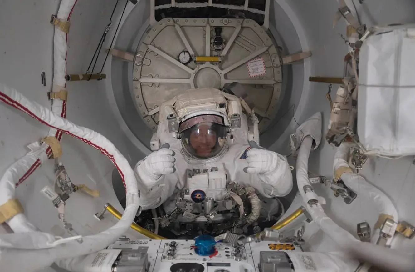 El astronauta de la NASA y comandante de la Expedición 63 es fotografiado con su traje espacial estadounidense a medio introducir en la sección de bloqueo de la esclusa de aire Quest, durante una caminata espacial para reemplazar baterías en la estructura del armazón Starboard-6 de la Estación Espacial Internacional. Crédito: NASA.