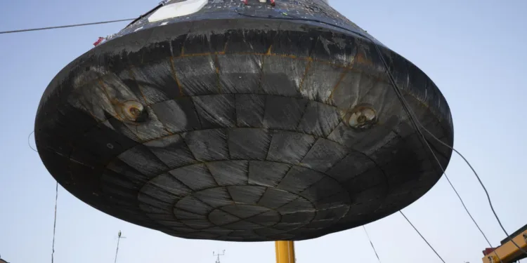 El módulo de tripulación Artemis II Orion luego de la recuperación, siendo elevado para su inspección tras ser descargado del buque de recuperación USS John P. Murtha. Las áreas hundidas, o círculos concéntricos más pequeños están asociadas con los pernos de separación que conectan el módulo de tripulación con el módulo de servicio. Los patrones circulares más grandes se forman debido al material de la almohadilla de compresión, lo que crea perturbaciones en el flujo causadas por el flujo de aire aerodinámico y térmico extremo durante la reentrada. Crédito: NASA/ Kevin Davis.
