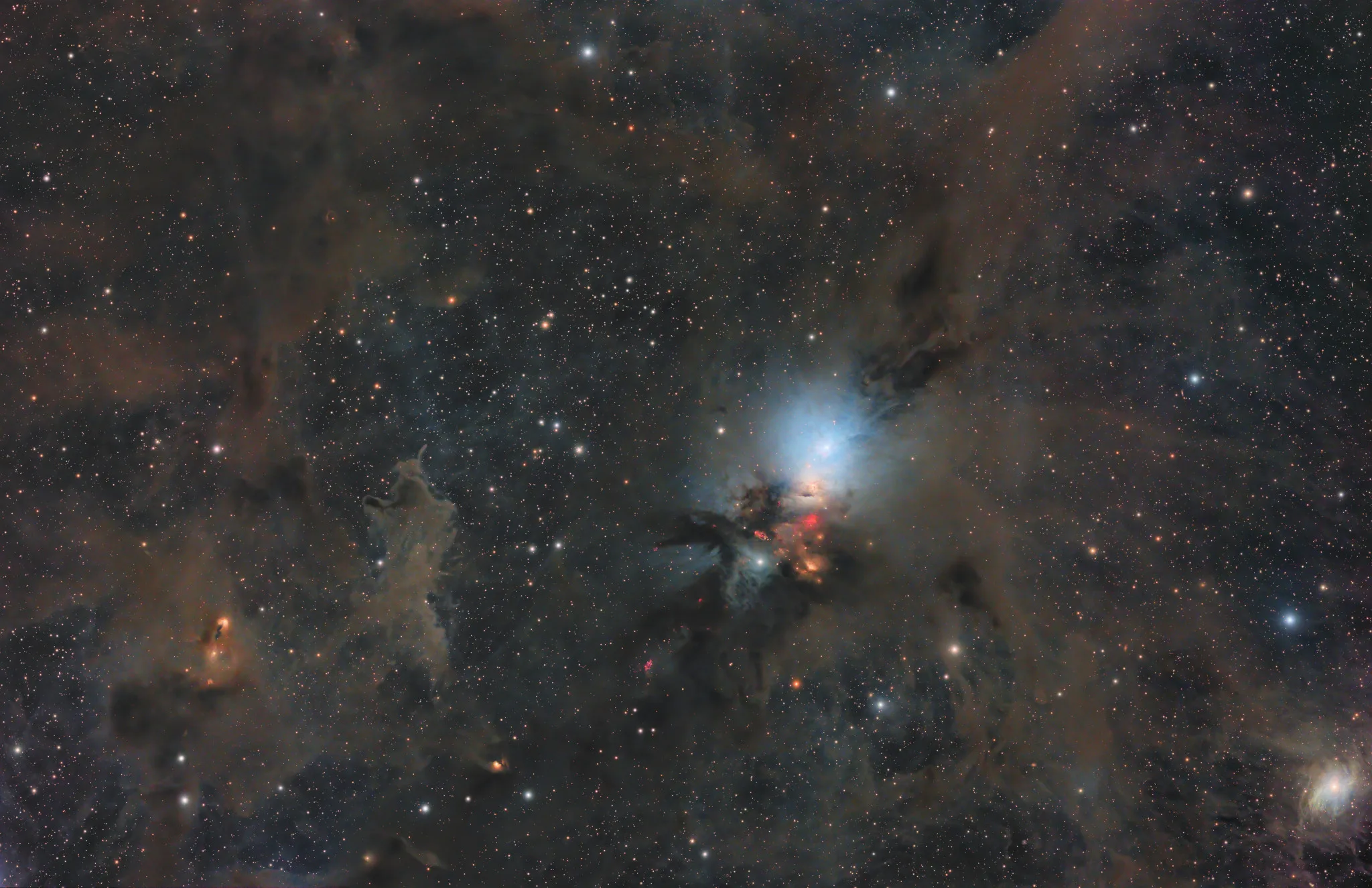 Imagen de la nube molecular de Perseo, una región de formación estelar donde destacan nebulosas de reflexión azuladas, nubes de polvo y emisiones rojizas producidas por estrellas jóvenes.